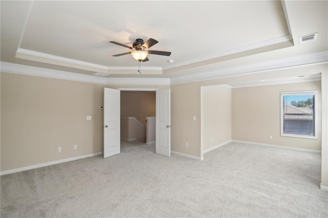 unfurnished bedroom featuring light carpet, a tray ceiling, visible vents, and baseboards