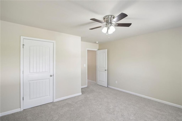 unfurnished bedroom featuring a ceiling fan, light colored carpet, and baseboards