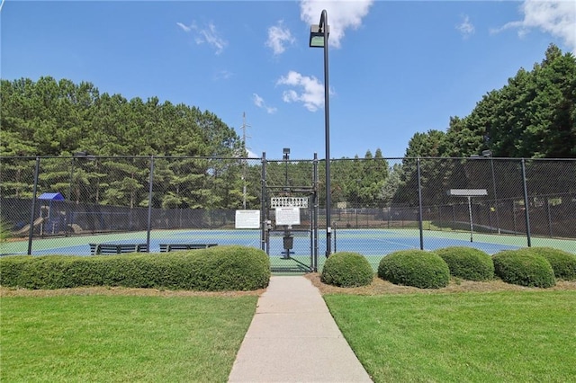 view of sport court featuring a gate, fence, and a lawn