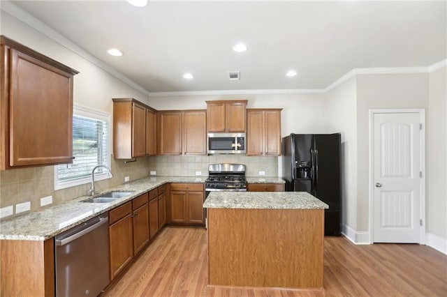 kitchen featuring stainless steel appliances, light wood finished floors, a sink, and a center island