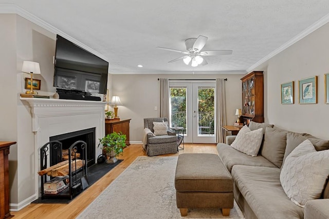 living room featuring ornamental molding, light wood-type flooring, ceiling fan, and french doors