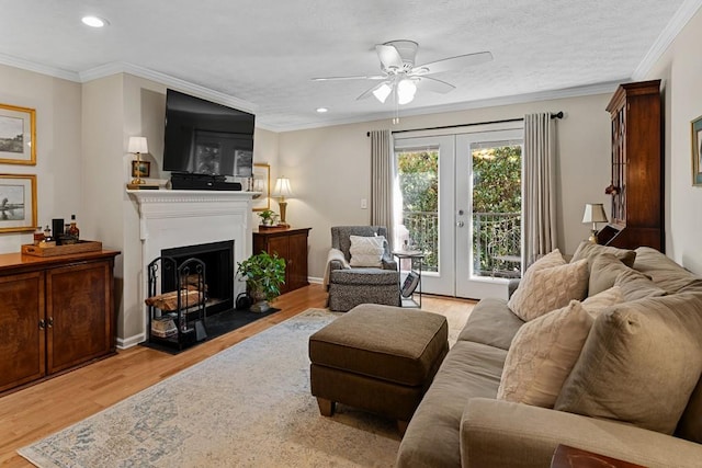 living room featuring a textured ceiling, light hardwood / wood-style flooring, french doors, ceiling fan, and ornamental molding