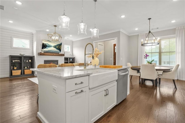 kitchen with stainless steel dishwasher, a glass covered fireplace, white cabinets, a sink, and dark wood finished floors