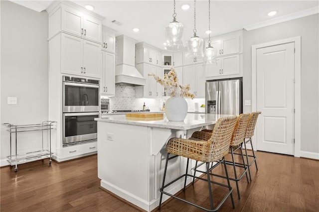 kitchen featuring white cabinetry, appliances with stainless steel finishes, premium range hood, and tasteful backsplash