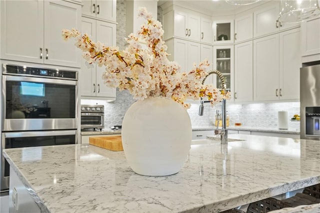 kitchen with decorative backsplash, a large island, a kitchen breakfast bar, light stone counters, and appliances with stainless steel finishes