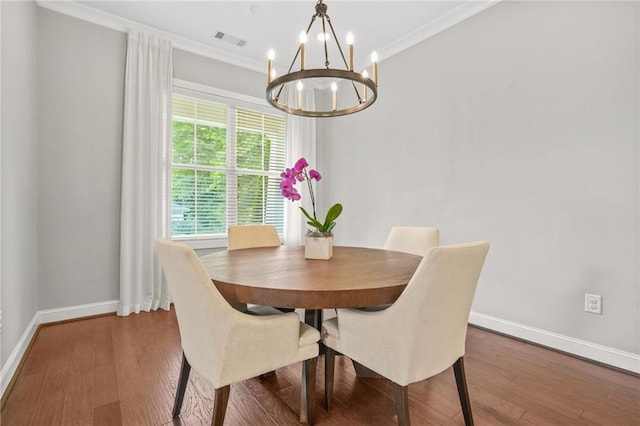 dining area with a chandelier, baseboards, visible vents, and wood finished floors