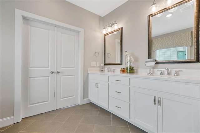 bathroom with double vanity, baseboards, a sink, and tile patterned flooring