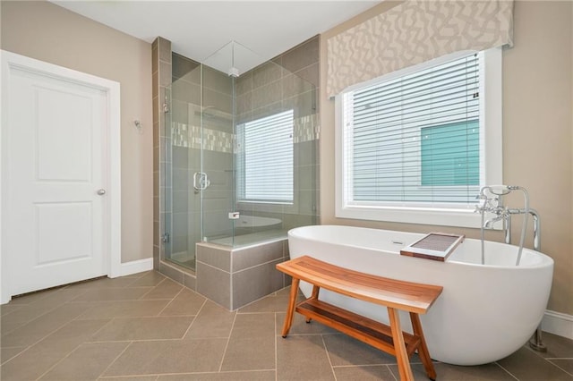 bathroom featuring a freestanding bath, tile patterned floors, baseboards, and a shower stall