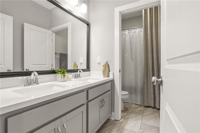 bathroom with double vanity, toilet, a sink, and marble finish floor