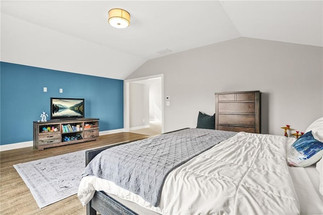 bedroom with baseboards, wood finished floors, and vaulted ceiling