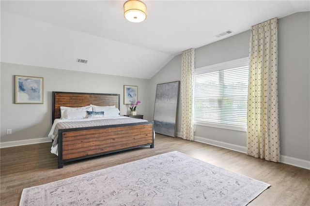 bedroom with visible vents, lofted ceiling, and wood finished floors