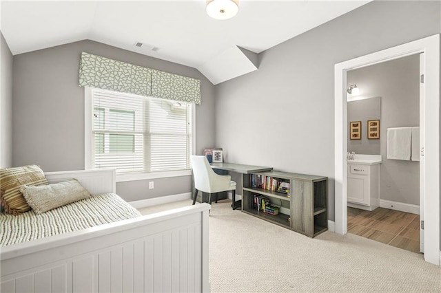 carpeted bedroom with baseboards, connected bathroom, lofted ceiling, and visible vents