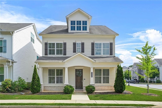 traditional style home with a shingled roof and a front yard