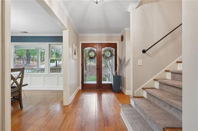 foyer with stairs, french doors, light wood-style flooring, visible vents, and ornamental molding