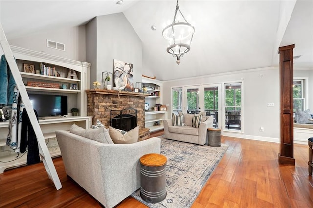 living room with hardwood / wood-style floors, high vaulted ceiling, baseboards, visible vents, and a stone fireplace