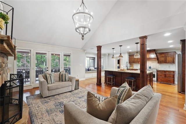 living area featuring light wood finished floors, high vaulted ceiling, decorative columns, and plenty of natural light