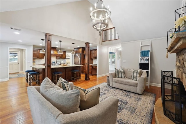 living room with high vaulted ceiling, baseboards, light wood finished floors, and visible vents