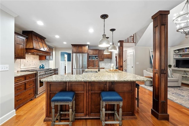 kitchen featuring light wood finished floors, a sink, stainless steel appliances, and custom exhaust hood