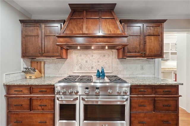 kitchen with double oven range, tasteful backsplash, ornamental molding, and premium range hood