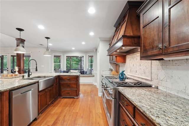 kitchen with crown molding, a sink, stainless steel appliances, and custom range hood