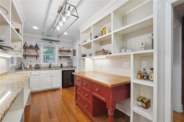 kitchen featuring crown molding, open shelves, light wood-type flooring, wine cooler, and a sink