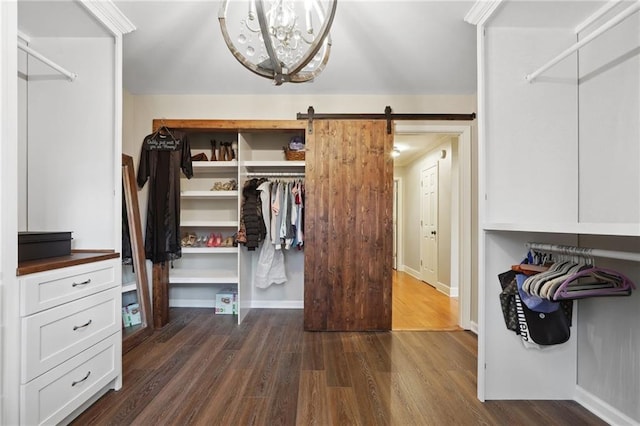 walk in closet featuring dark wood finished floors, a barn door, and a chandelier