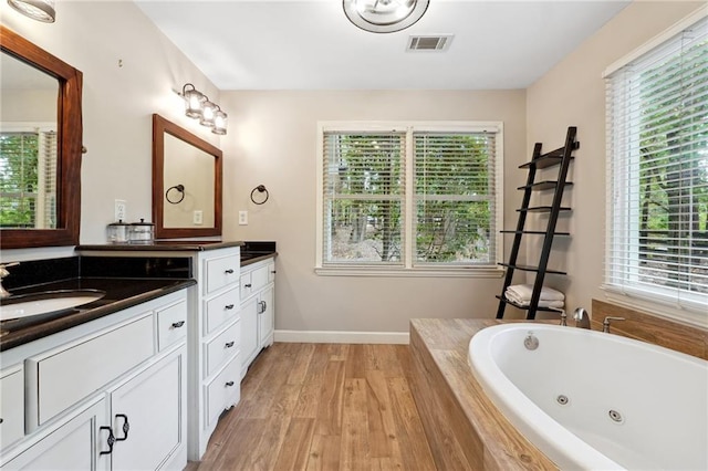 bathroom featuring vanity, a jetted tub, wood finished floors, baseboards, and visible vents