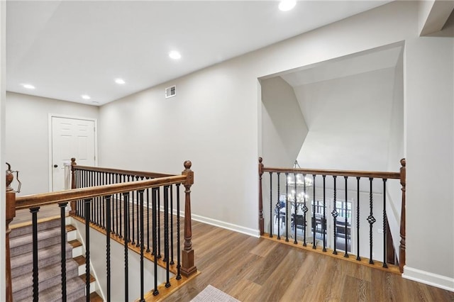 corridor featuring an upstairs landing, recessed lighting, baseboards, visible vents, and wood finished floors