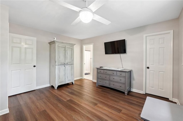unfurnished bedroom with baseboards, ensuite bath, ceiling fan, and dark wood-type flooring
