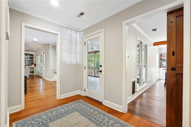 foyer entrance with baseboards, visible vents, wood finished floors, and ornamental molding