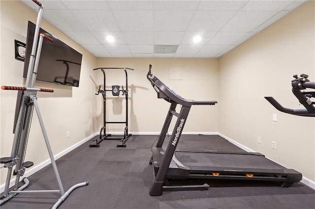 exercise area with baseboards and a paneled ceiling