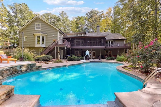 outdoor pool with a patio, a sunroom, a wooden deck, and stairs