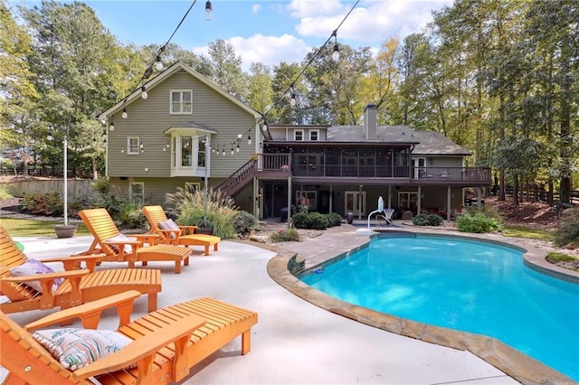 rear view of property featuring stairs, a wooden deck, a sunroom, and a patio area