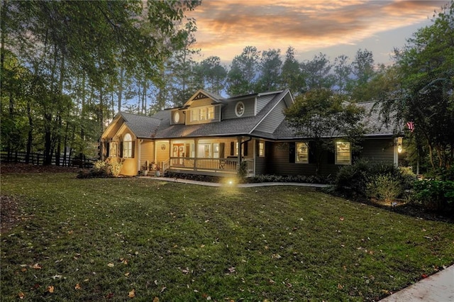 back of house at dusk with fence and a yard