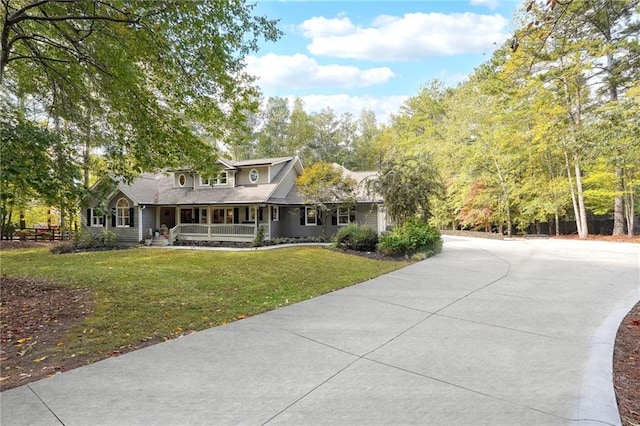 view of front facade with driveway, covered porch, and a front yard