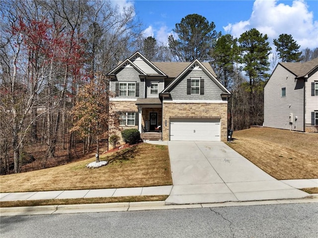 view of front of property with stone siding, a front yard, an attached garage, and driveway