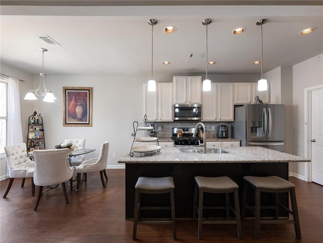 kitchen featuring visible vents, backsplash, dark wood finished floors, appliances with stainless steel finishes, and a sink