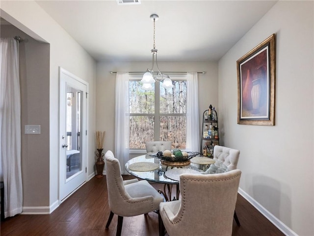 dining room with dark wood finished floors, visible vents, a chandelier, and baseboards