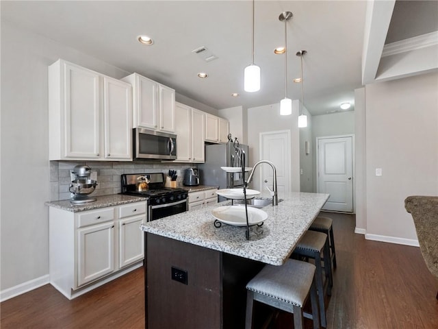 kitchen featuring decorative backsplash, white cabinets, dark wood-style floors, and appliances with stainless steel finishes