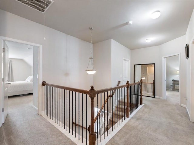 hall featuring baseboards, visible vents, attic access, light carpet, and an upstairs landing