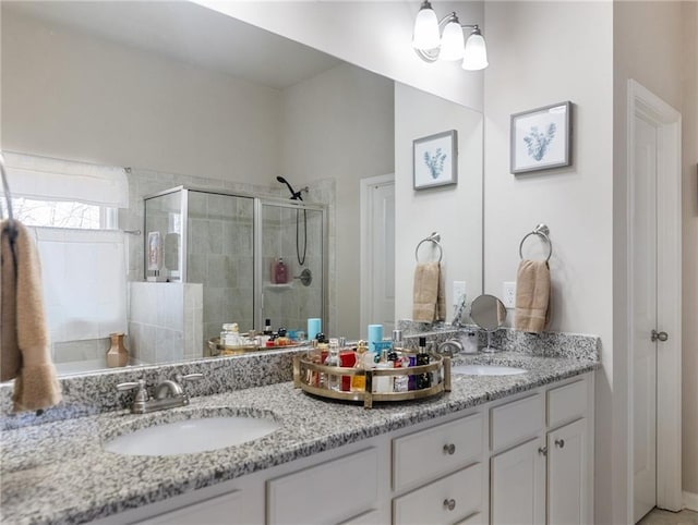 full bathroom with a sink, a stall shower, and double vanity