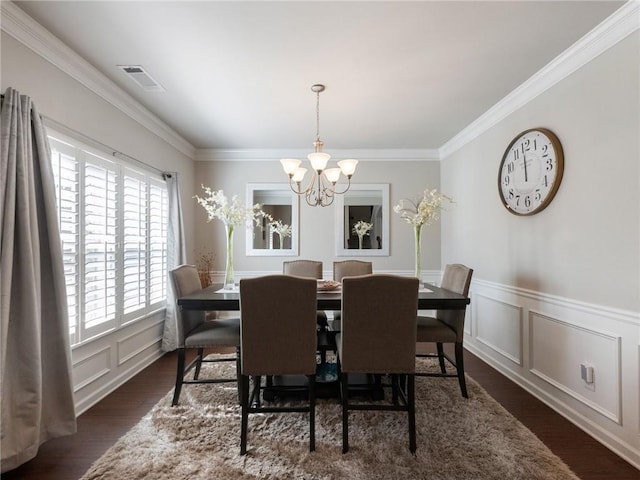 dining area with visible vents, a decorative wall, an inviting chandelier, and wood finished floors