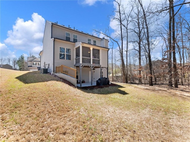 rear view of house featuring a yard, central AC unit, a sunroom, and a chimney