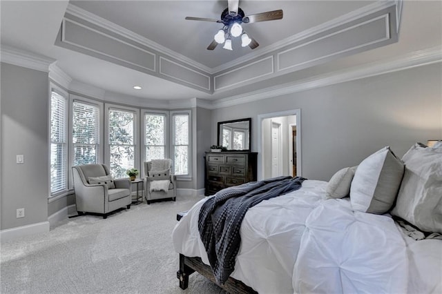 carpeted bedroom with a tray ceiling, baseboards, ornamental molding, and a ceiling fan