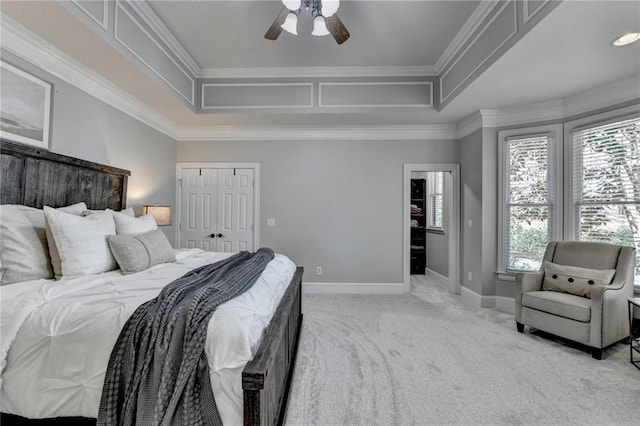 bedroom featuring baseboards, light colored carpet, ornamental molding, a raised ceiling, and a ceiling fan