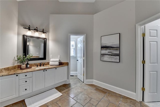 bathroom with stone tile floors, vanity, and baseboards