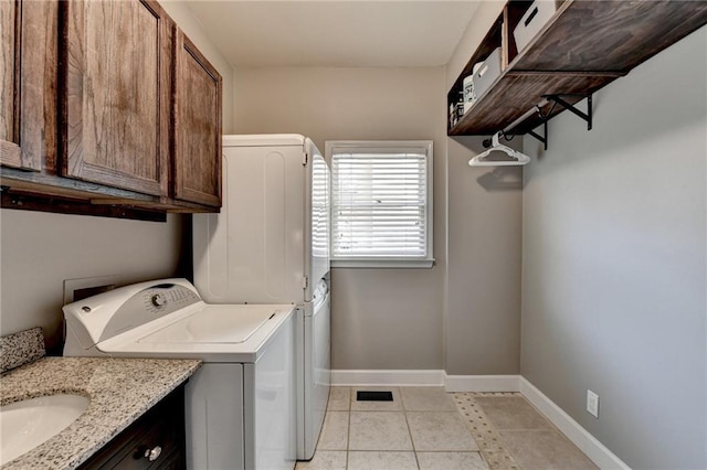 washroom with washer / dryer, light tile patterned floors, cabinet space, and baseboards