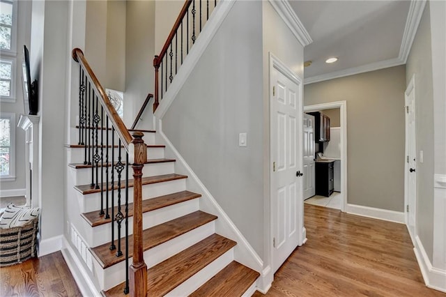 stairs with recessed lighting, crown molding, baseboards, and wood finished floors