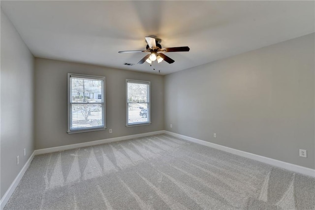 spare room with light carpet, visible vents, ceiling fan, and baseboards