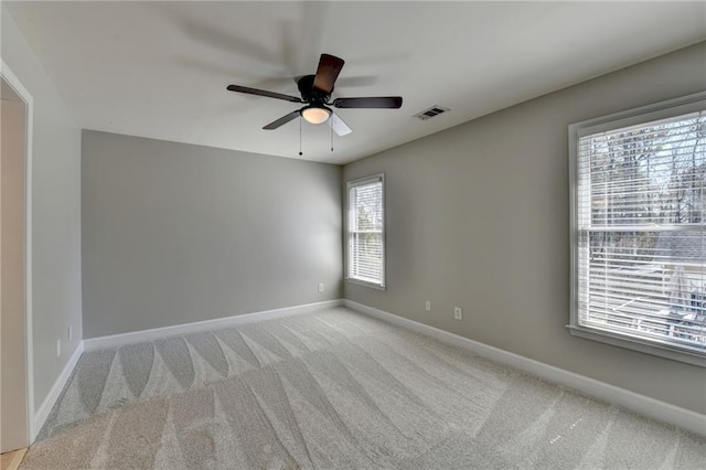 spare room featuring light carpet, visible vents, ceiling fan, and baseboards